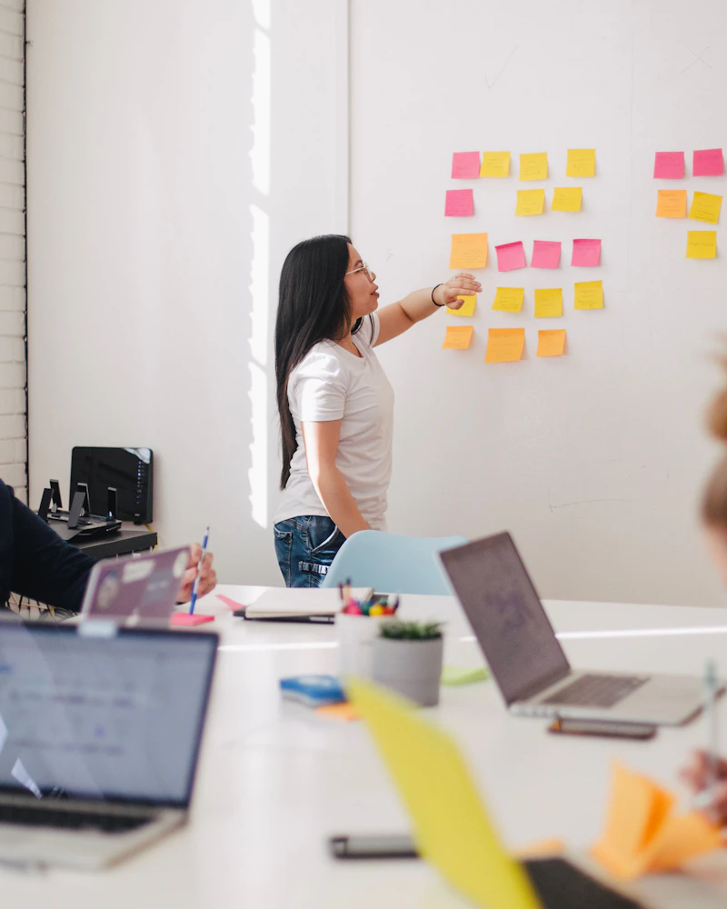 Une femme disposant des post-it colorés sur un tableau blanc pendant une session de planification