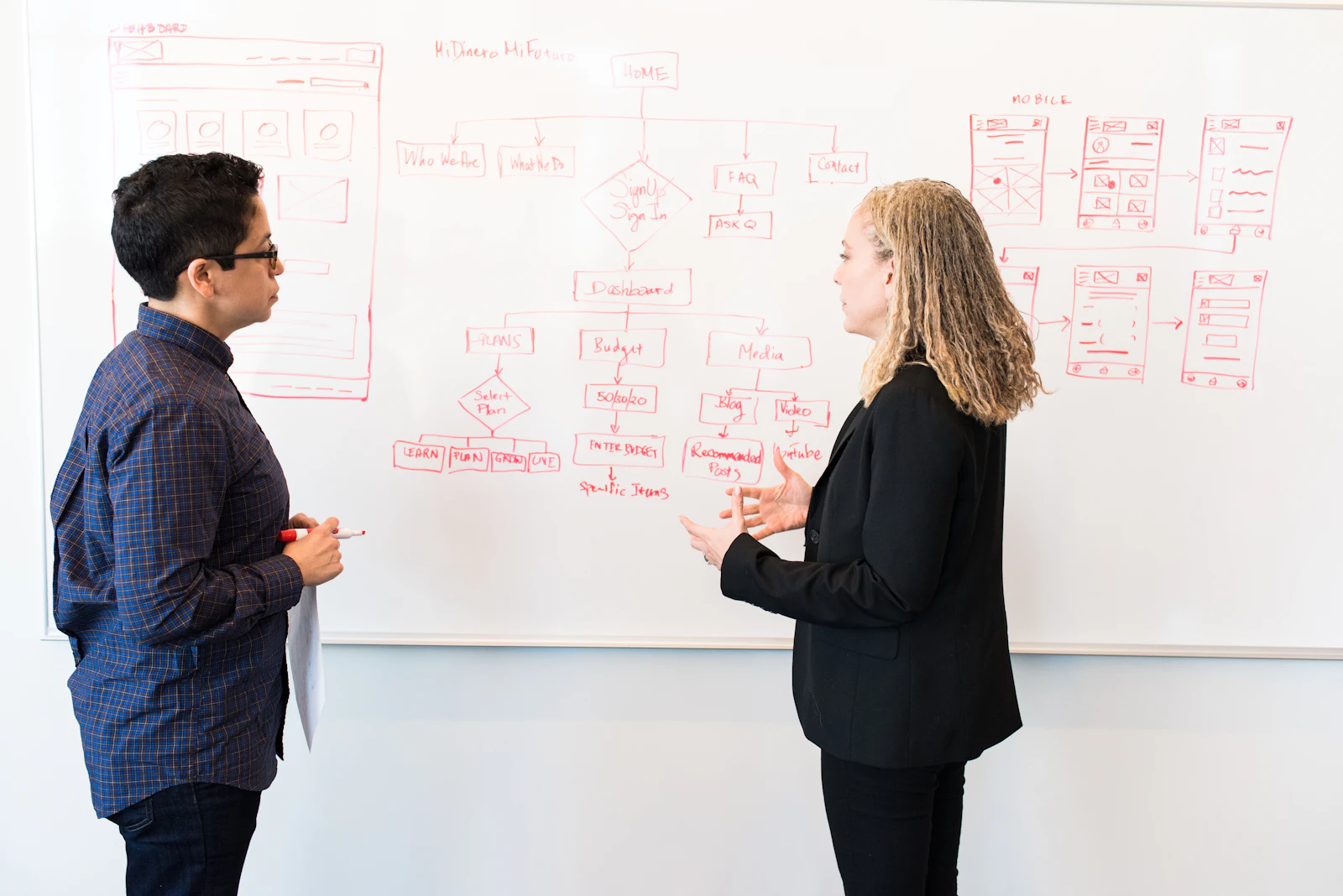 Deux personnes échangent devant un tableau blanc lors d'une session de travail technique